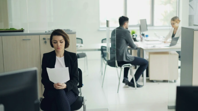 Woman sitting in office holding papers